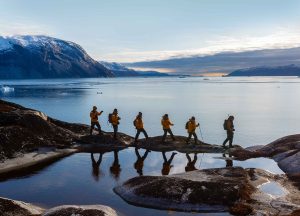 Luxury travelers walking on rocks at a lake - Utopian Adventures